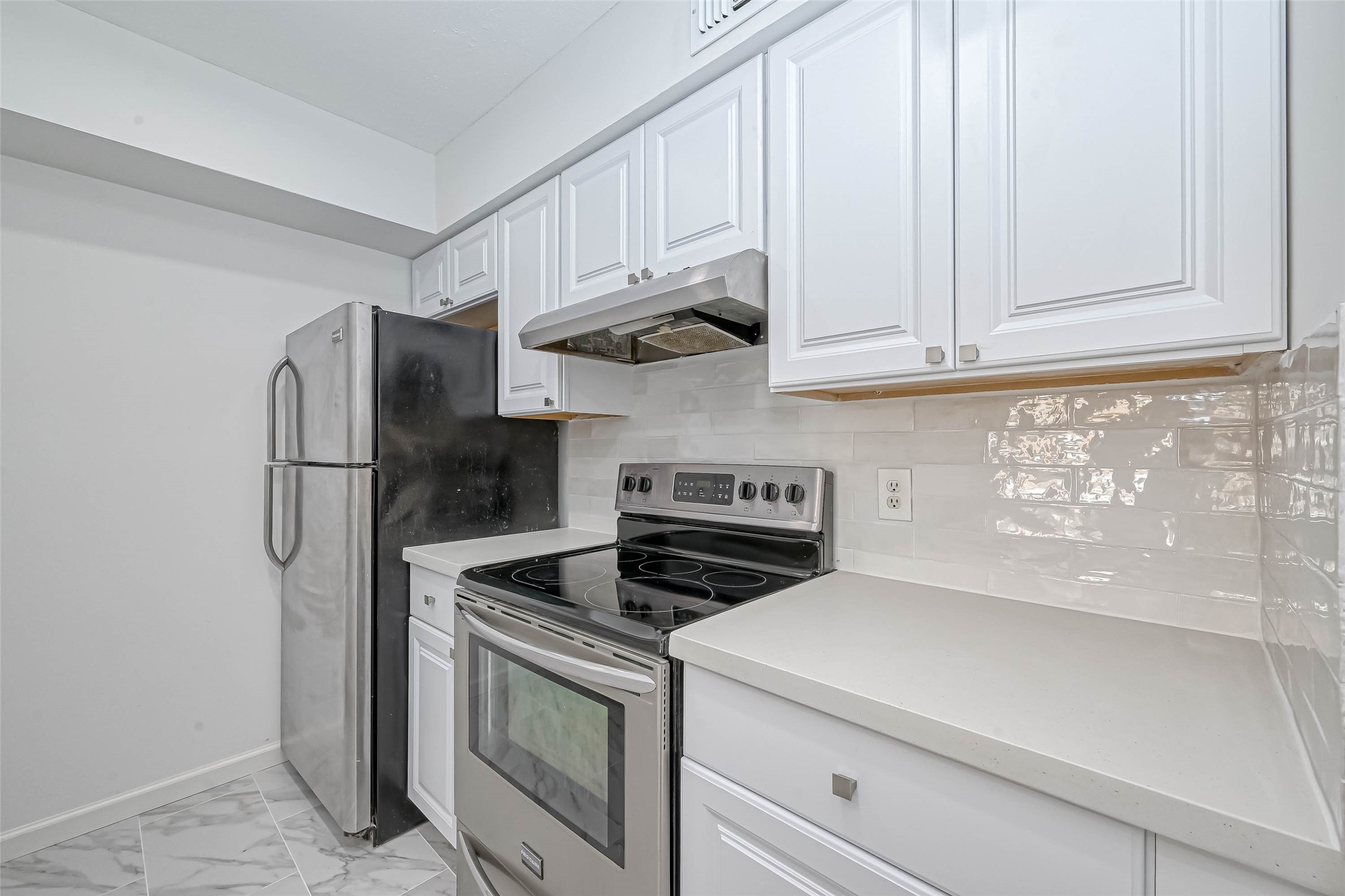 4645 Wild Indigo Street, Unit 375 Houston, TX 77027 - Photo 5 of 27 a kitchen with stainless steel appliances granite countertop white cabinets and a refrigerator