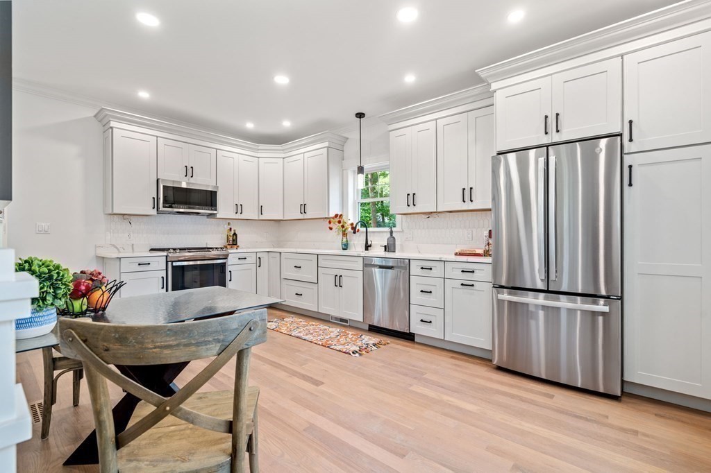 504 Hudson Road Sudbury, MA 01776 - Photo 15 of 42 a kitchen with white cabinets stainless steel appliances and wooden floor