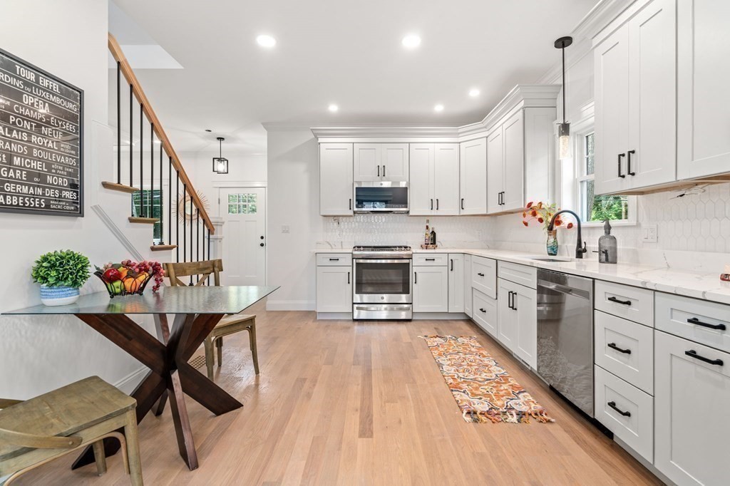 504 Hudson Road Sudbury, MA 01776 - Photo 19 of 42 a kitchen with stainless steel appliances kitchen island granite countertop a stove top oven a sink a dining table and chairs with wooden floor