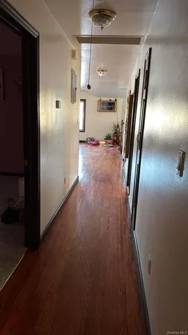 a hallway with a couch and a dining table with wooden floor