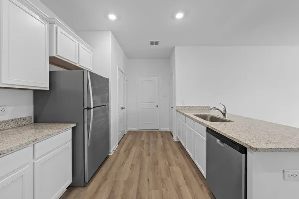 a kitchen with a sink a refrigerator and wooden floor