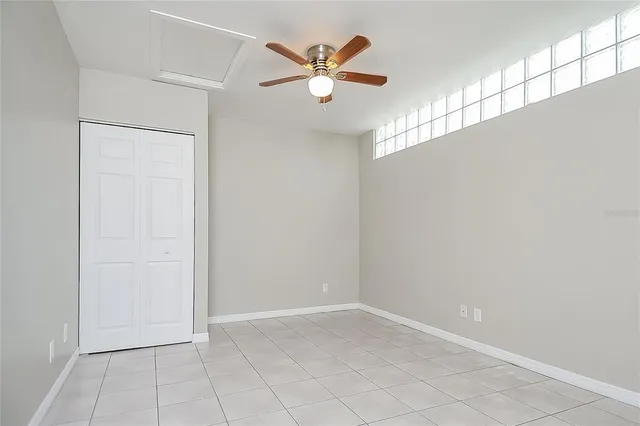 an empty room with ceiling fan and window