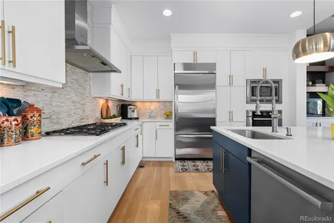 a kitchen with stainless steel appliances granite countertop wooden floor a dining table chairs stove and white cabinets