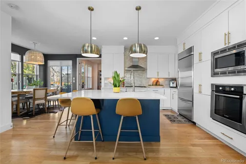 a kitchen with stainless steel appliances granite countertop a sink a stove and a wooden floors