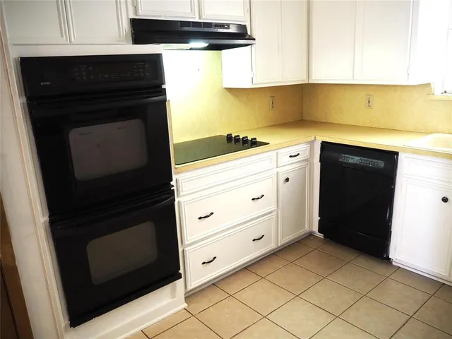 a kitchen with granite countertop white cabinets and black appliances