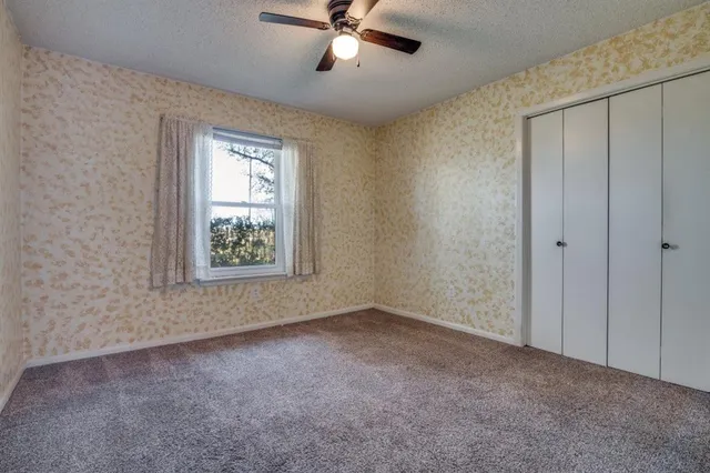 an empty room with windows and fan