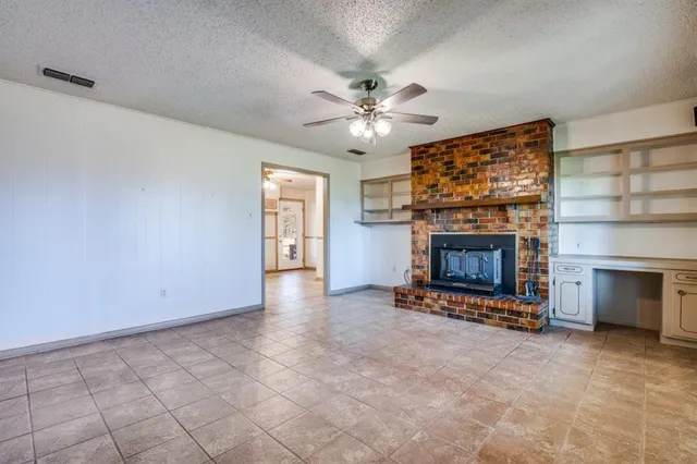a view of an empty room with a fireplace and a window