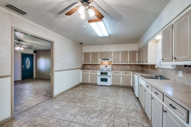 a large kitchen with stainless steel appliances granite countertop a sink and cabinets