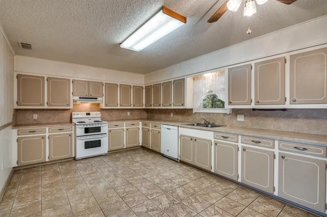 a kitchen with granite countertop white cabinets and white stainless steel appliances