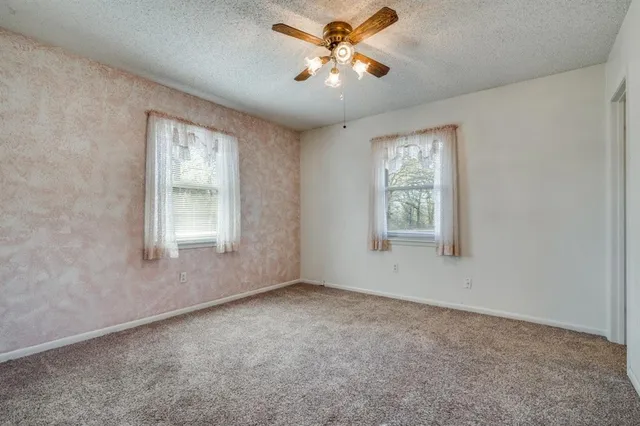 an empty room with windows and ceiling fan