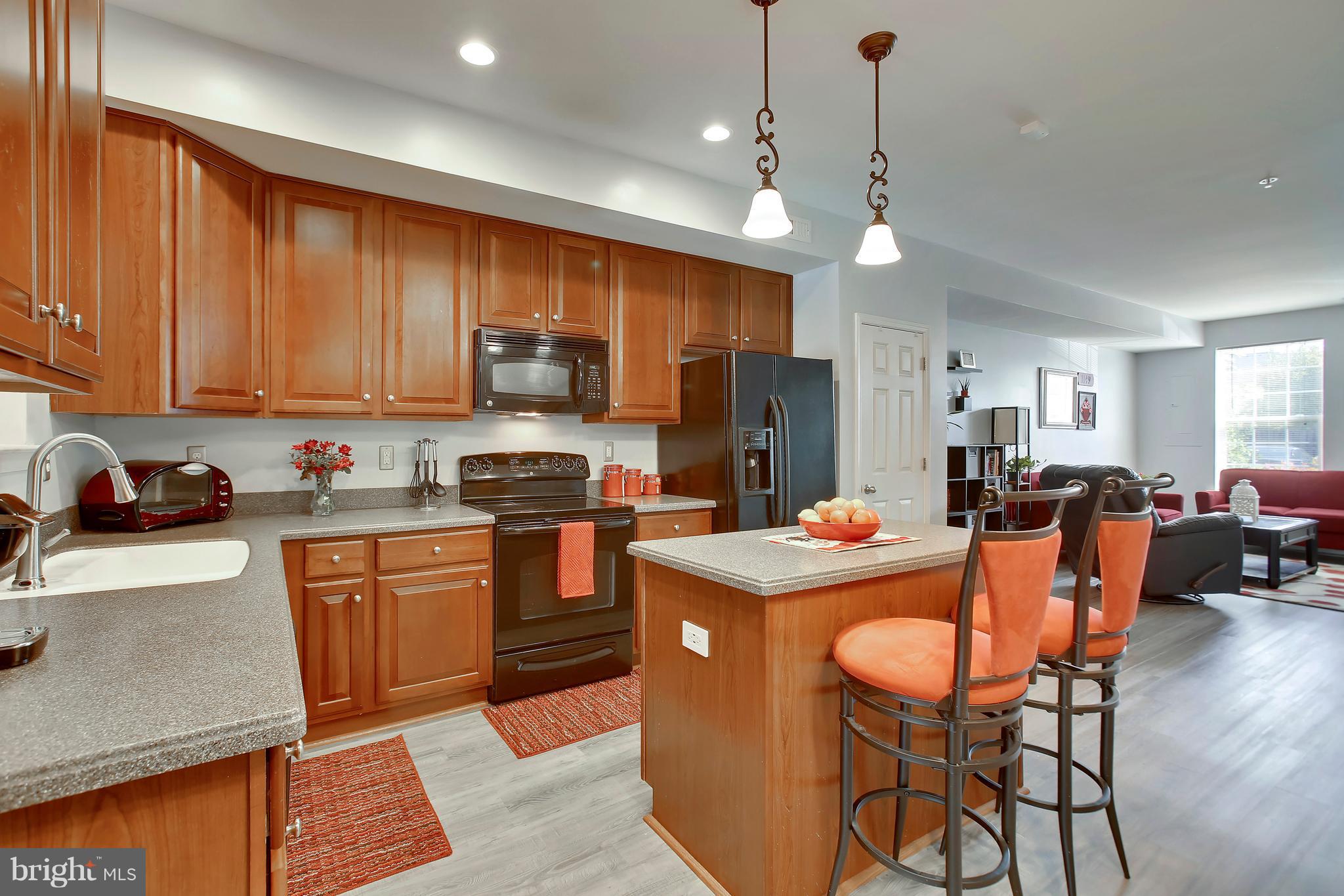 643 Tivoli Road Frederick, MD 21703 - Photo 9 of 30 a kitchen with stainless steel appliances granite countertop a stove top oven a refrigerator a sink dishwasher a dining table and chairs with wooden floor