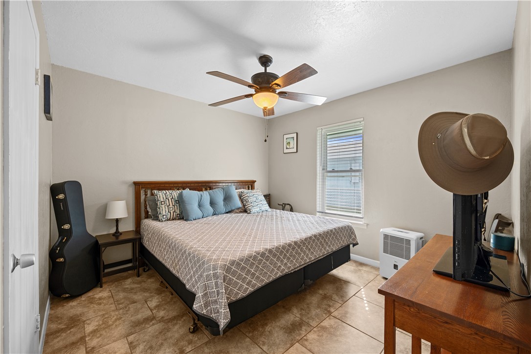 464 Sunset Ingleside, TX 78362 - Photo 21 of 35 a bedroom with a bed a computer on a desk and a potted plant