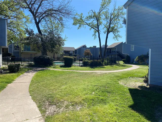 a view of a swimming pool with a yard and palm trees