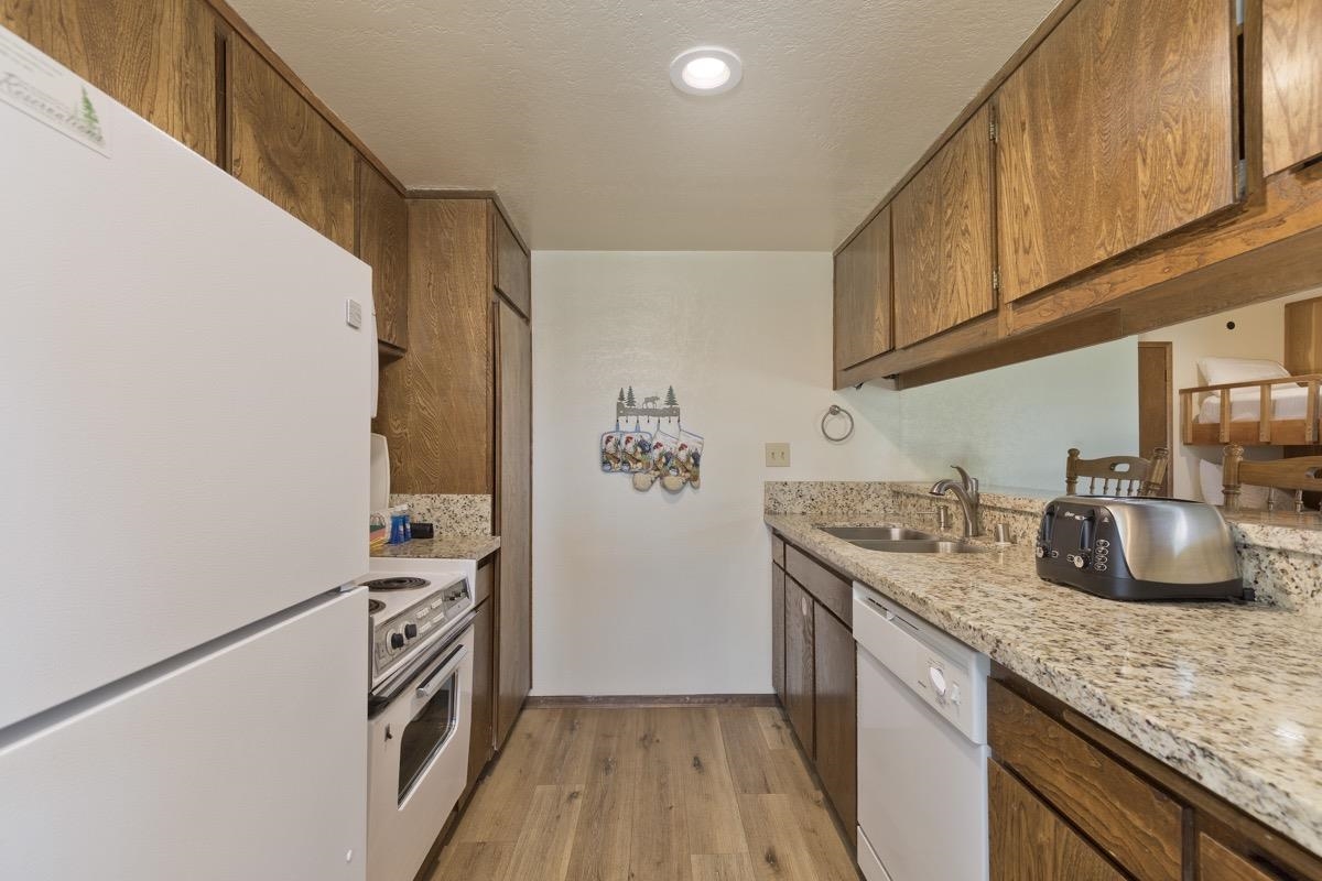 25 Lee Road, Unit 111 Mammoth Lakes, CA 93546 - Photo 14 of 32 a kitchen with granite countertop a sink a stove and cabinets