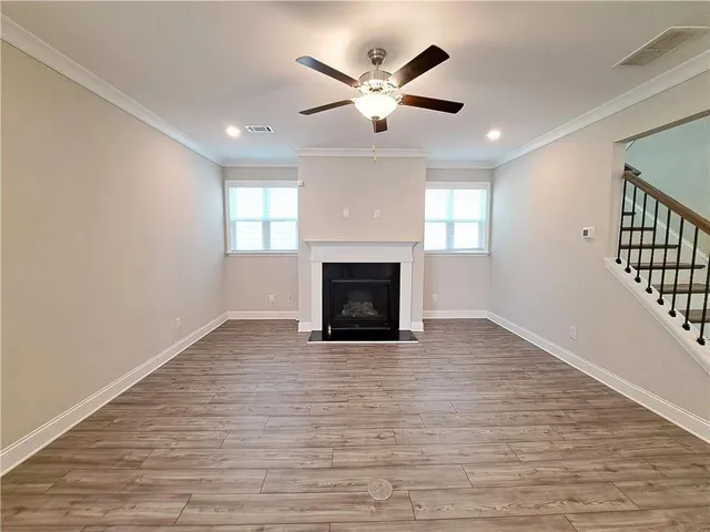 an empty room with wooden floor fireplace and windows