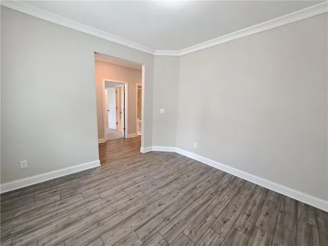 a view of an empty room with wooden floor and closet