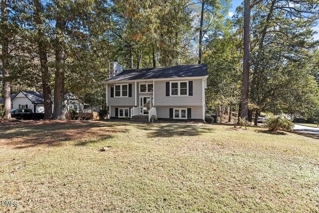 a front view of a house with a yard covered with snow and trees