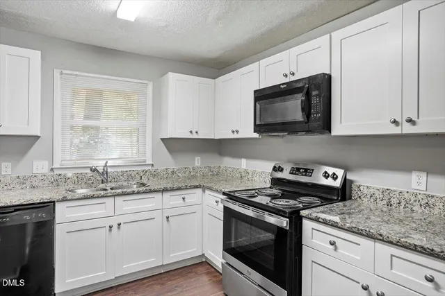 a kitchen with stainless steel appliances granite countertop white cabinets granite counter tops and a wooden floors