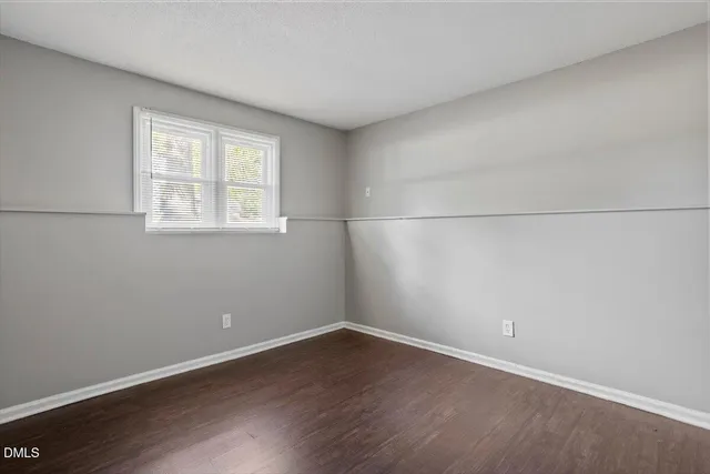 an empty room with wooden floor and window