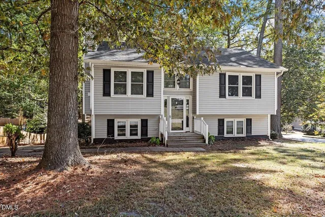 a front view of a house with large trees