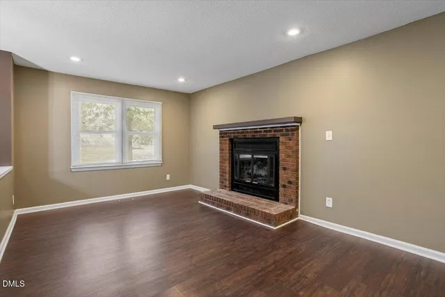an empty room with wooden floor and fireplace