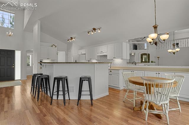 7820 Midnight Road Peyton, CO 80831 - Photo 5 of 10 Kitchen with rail lighting, light hardwood / wood-style flooring, hanging light fixtures, and white cabinets