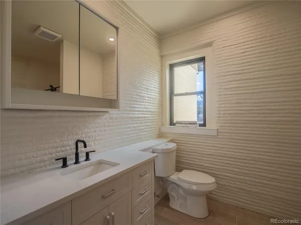a bathroom with a toilet a sink a mirror and vanity