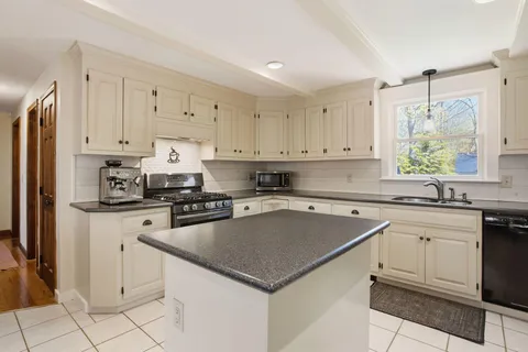 a kitchen with granite countertop a sink dishwasher stove and white cabinets