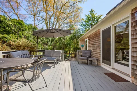 a view of a patio with table and chairs under an umbrella with wooden floor