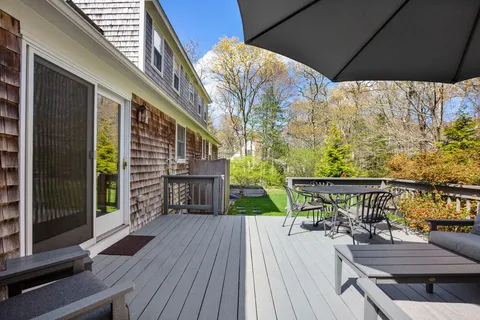 a balcony with wooden floor table and chairs