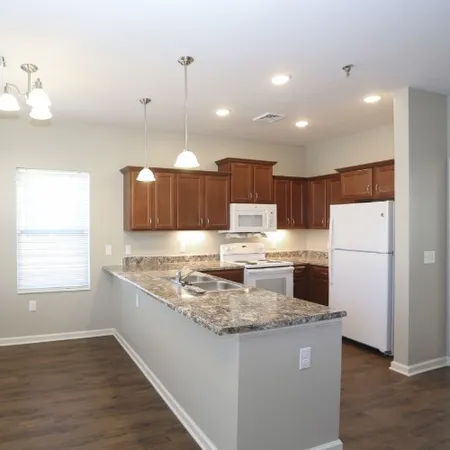 a kitchen with kitchen island a stove a refrigerator a sink dishwasher with a dining table and chairs