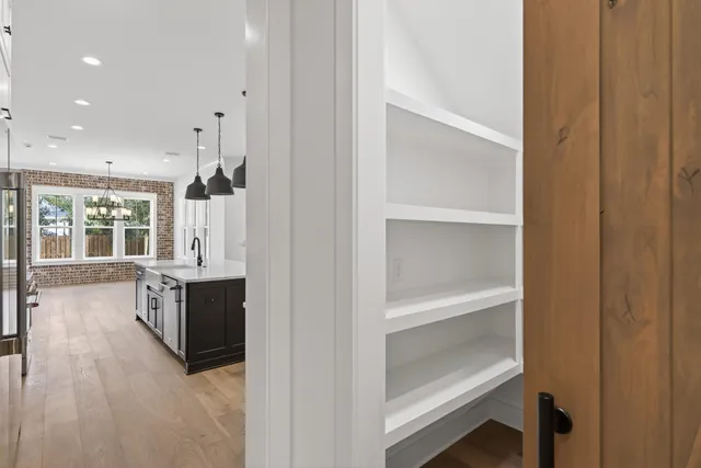 a large white kitchen with granite countertop a refrigerator a sink dishwasher a dining table and chairs with wooden floor