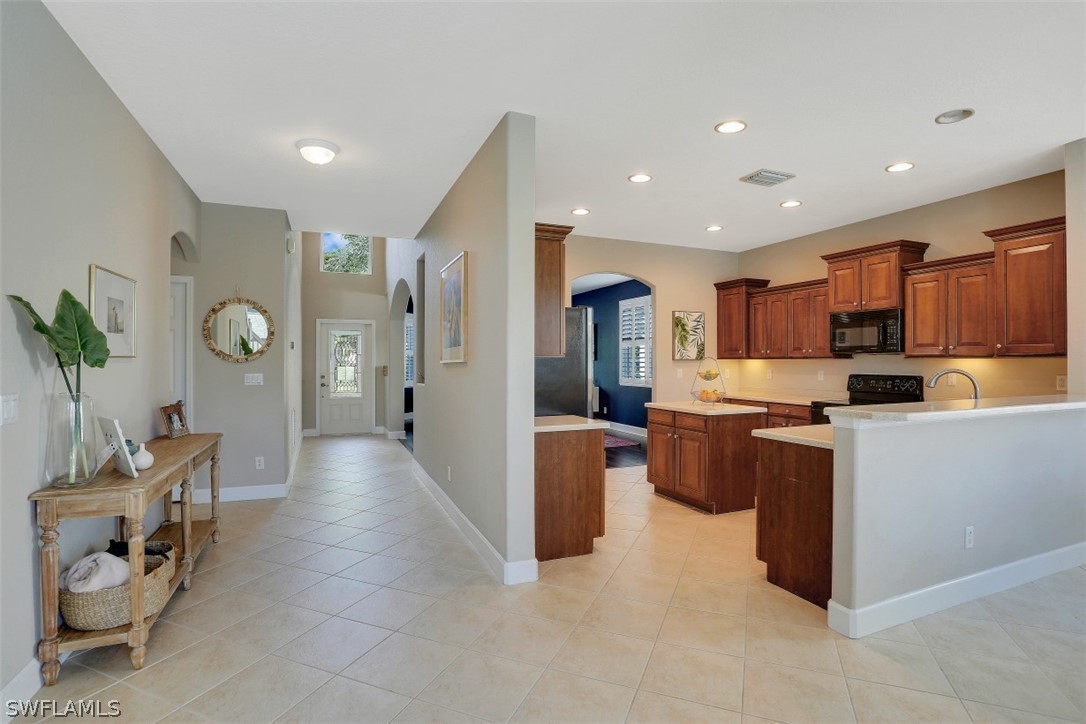 a large open kitchen with stainless steel appliances kitchen island granite countertop a refrigerator and a sink