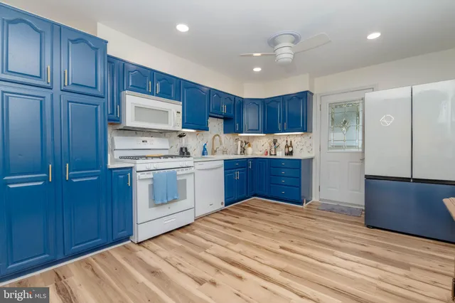 a kitchen with kitchen island granite countertop wooden cabinets and white stainless steel appliances