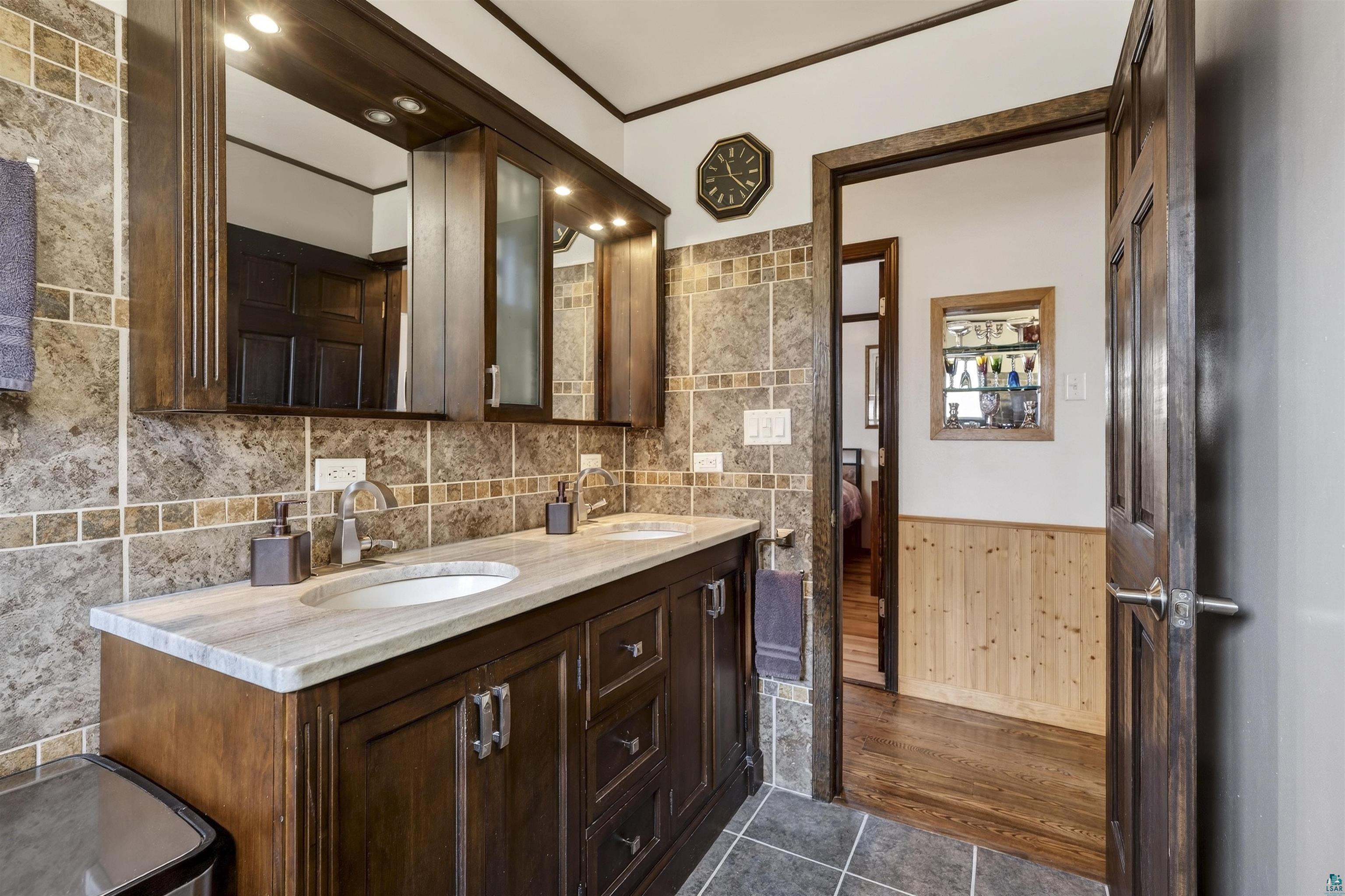 11702 East Mail Road Gordon, WI 54838 - Photo 41 of 49 Bathroom with wainscoting, double vanity, dark tile patterned floors, wooden walls, and ornamental molding