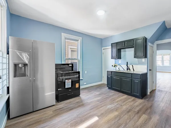 a kitchen with stainless steel appliances kitchen island granite countertop a refrigerator a sink dishwasher and a stove with wooden floor