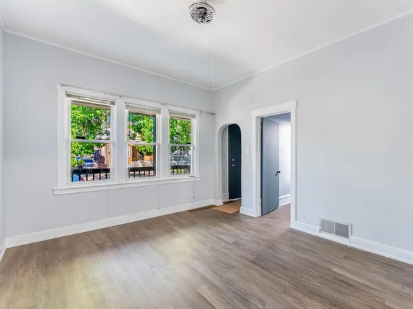 an empty room with wooden floor and windows