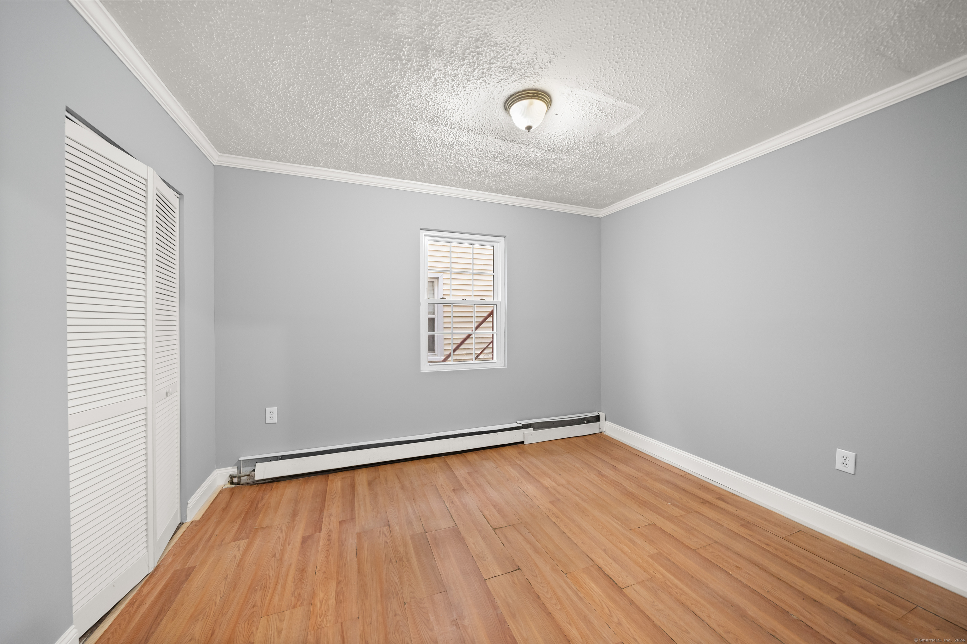 666 Ogden Street, Unit 1 Bridgeport, CT 06608 - Photo 5 of 10 an empty room with wooden floor and windows