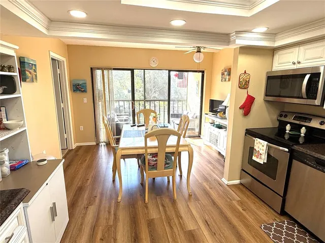 a living room with furniture a large window wooden floor and stainless steel appliances