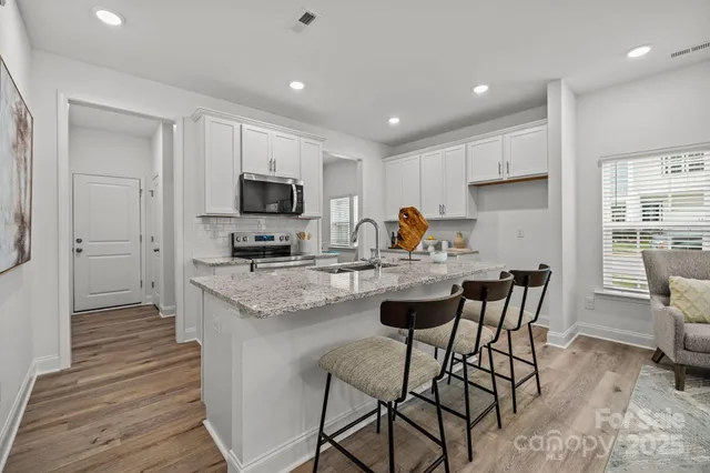 a kitchen with granite countertop a stove a sink and a refrigerator
