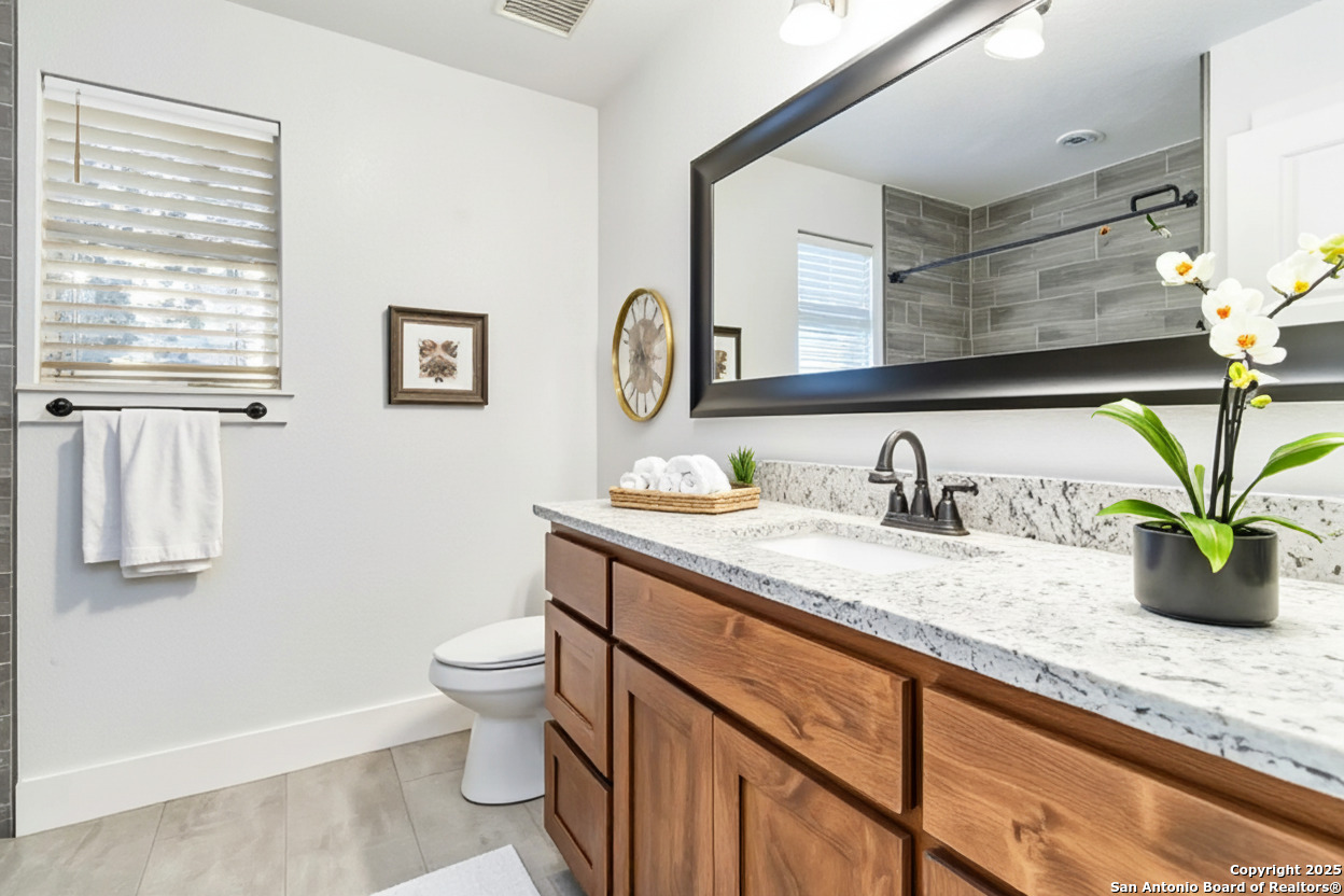 188 Old Camp Road Bandera, TX 78003 - Photo 18 of 36 a bathroom with a granite countertop sink a toilet and a mirror