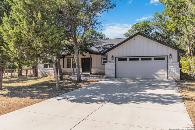 a view of a house with a yard and large tree