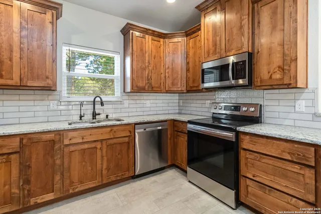 a kitchen with stainless steel appliances granite countertop a sink stove and microwave