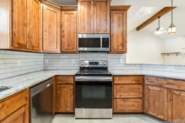 a kitchen with granite countertop a sink stainless steel appliances and cabinets