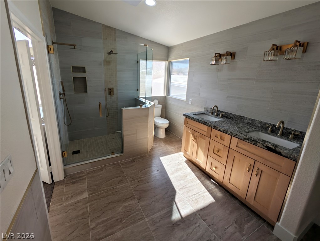 104 Appian Way Henderson, NV 89002 - Photo 15 of 37 Bathroom featuring lofted ceiling, double vanity, tile walls, and a stall shower