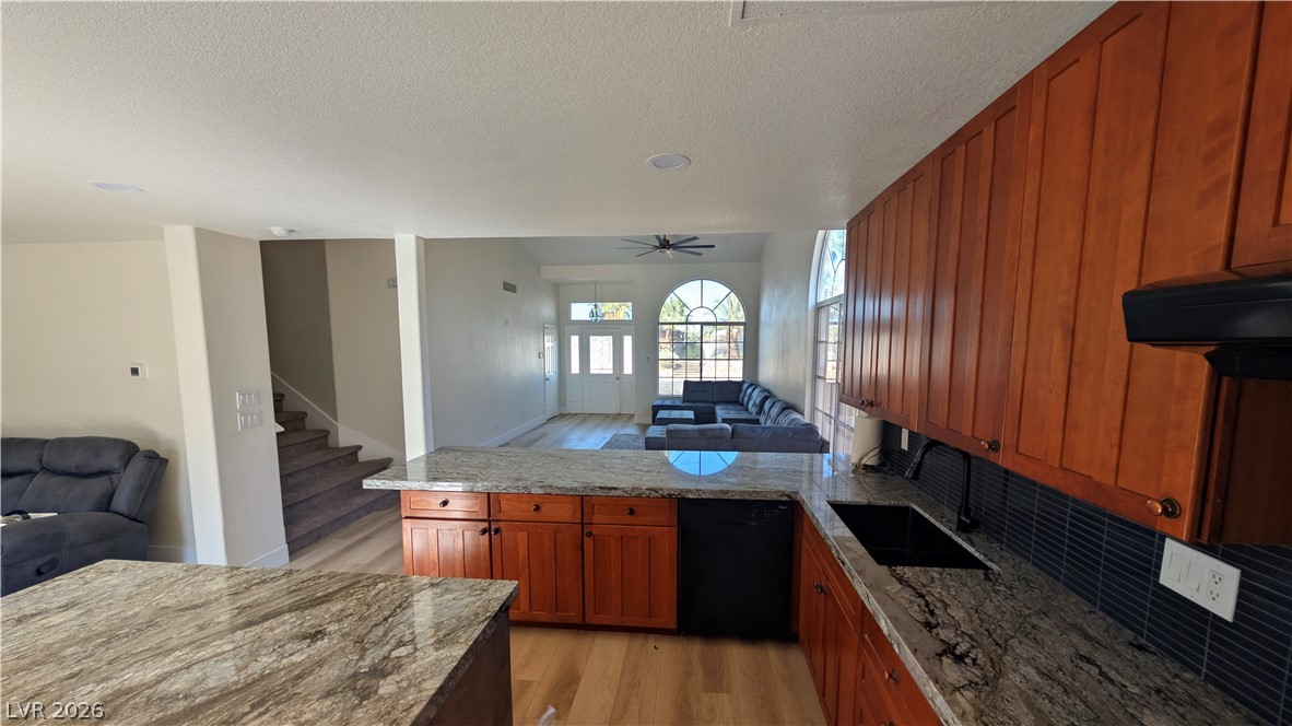 104 Appian Way Henderson, NV 89002 - Photo 36 of 37 Kitchen featuring open floor plan, a peninsula, light stone counters, wood finish cabinetry, and a ceiling fan