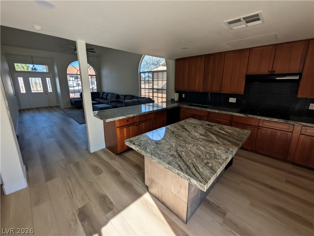104 Appian Way Henderson, NV 89002 - Photo 37 of 37 Kitchen featuring light stone countertops, open floor plan, a peninsula, light wood finished floors, and wood finish cabinets
