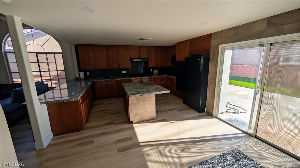 104 Appian Way Henderson, NV 89002 - Photo 27 of 37 Kitchen with freestanding refrigerator, a kitchen island, light wood-style flooring, and dark stone countertops