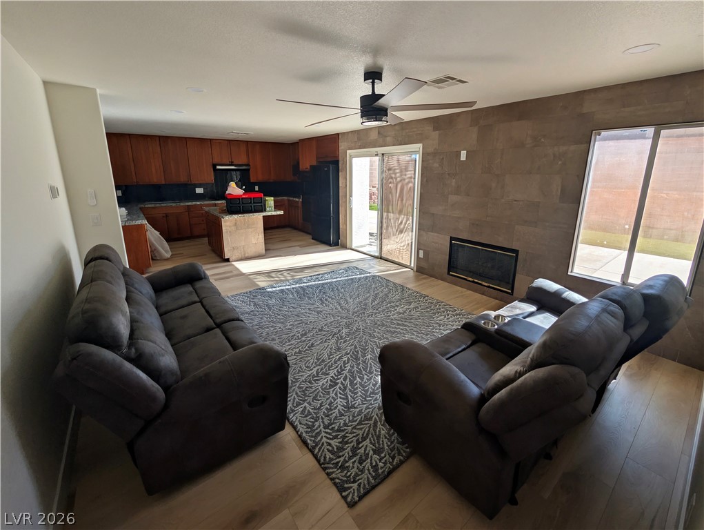 104 Appian Way Henderson, NV 89002 - Photo 30 of 37 Living area with light wood finished floors, a tiled fireplace, and ceiling fan