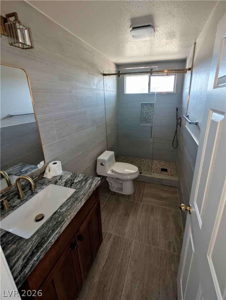 104 Appian Way Henderson, NV 89002 - Photo 10 of 37 Bathroom with vanity, tile walls, a stall shower, and a textured ceiling